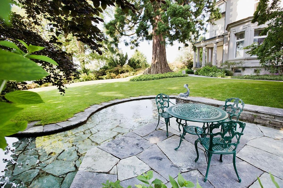 Nahaufnahme eines künstlichen Teichs aus Natursteinplatten im Garten der Klinik Meissenberg. 